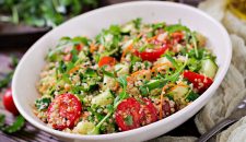 Salads with quinoa,  arugula, radish, tomatoes and cucumber in bowl on  wooden background.  Healthy food, diet, detox and vegetarian concept.