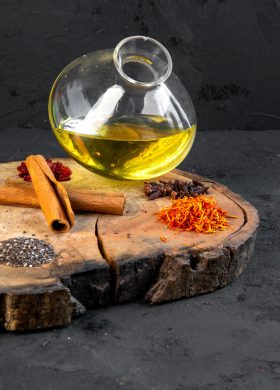 side view olive oil in a jug with spices on a cinnamon plate