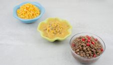 Three bowls of boiled corn, soup and beans on white surface. High quality photo